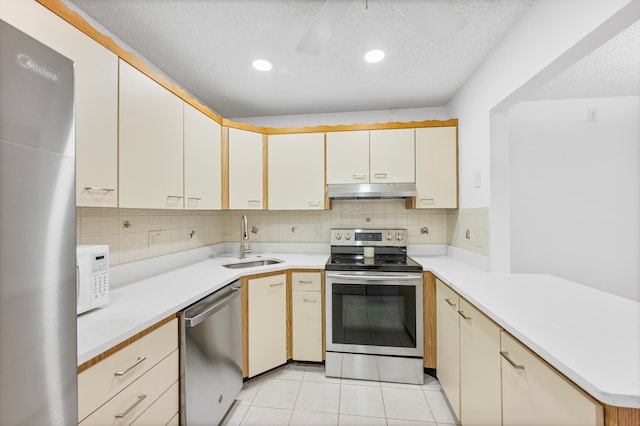 kitchen with sink, light tile patterned floors, a textured ceiling, tasteful backsplash, and stainless steel appliances