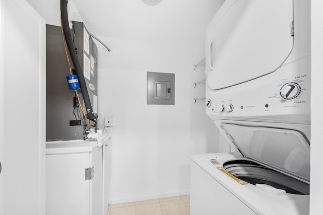 laundry area featuring electric panel, light tile patterned flooring, and stacked washer / drying machine