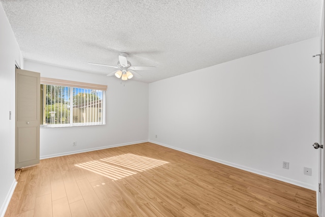 empty room with ceiling fan, light wood-type flooring, and a textured ceiling