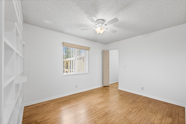 spare room with a textured ceiling, light wood-type flooring, and ceiling fan