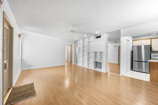 unfurnished living room with a textured ceiling, light hardwood / wood-style floors, and built in features