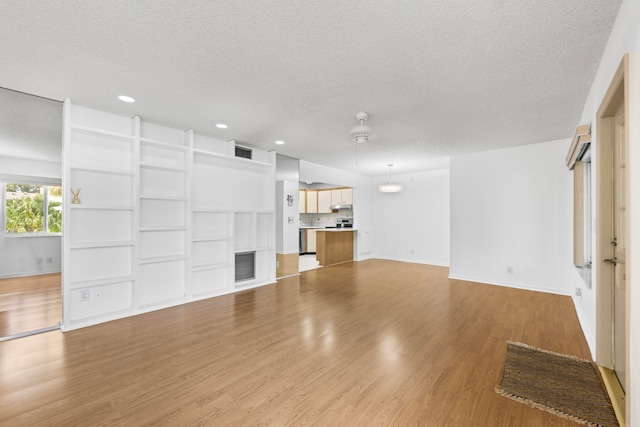 unfurnished living room with ceiling fan, a textured ceiling, and light hardwood / wood-style flooring