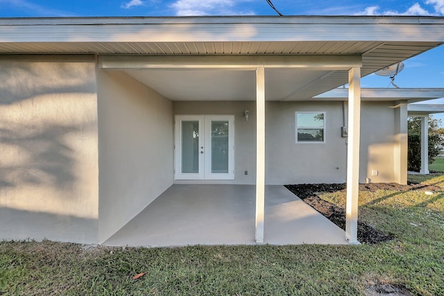 entrance to property featuring a lawn, a patio area, and french doors