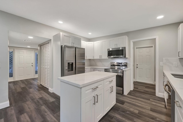 kitchen with a center island, white cabinets, stainless steel appliances, and dark hardwood / wood-style floors