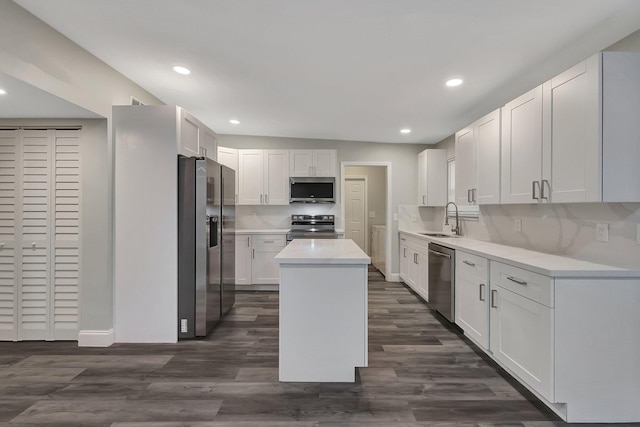 kitchen with appliances with stainless steel finishes, dark hardwood / wood-style flooring, sink, a center island, and white cabinetry