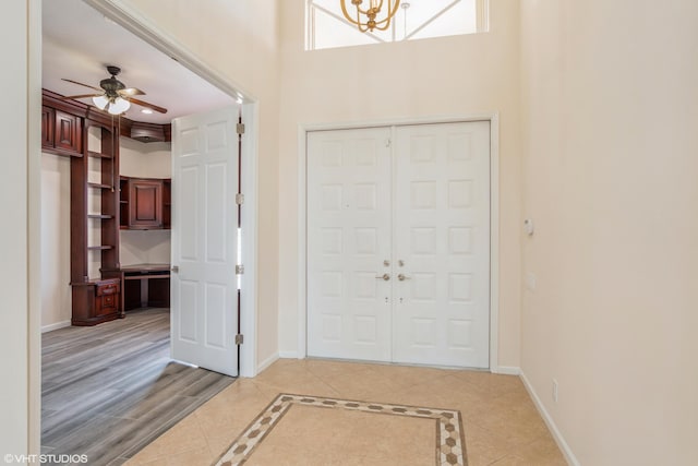 entrance foyer featuring ceiling fan, light wood-type flooring, and a towering ceiling