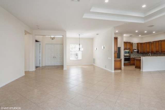 unfurnished living room with light tile patterned floors, a raised ceiling, and a notable chandelier