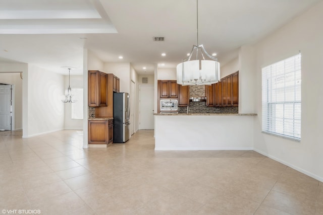 kitchen with decorative backsplash, an inviting chandelier, decorative light fixtures, and appliances with stainless steel finishes