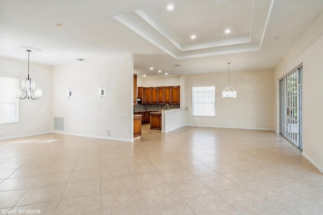 unfurnished living room featuring an inviting chandelier, a raised ceiling, and light tile patterned flooring