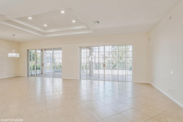 tiled empty room featuring a raised ceiling and a wealth of natural light