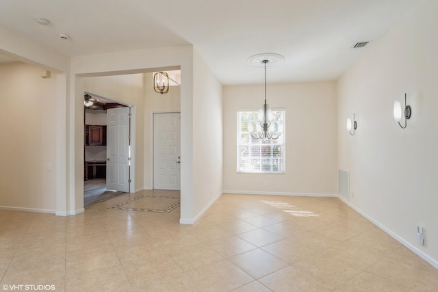 tiled spare room featuring ceiling fan with notable chandelier