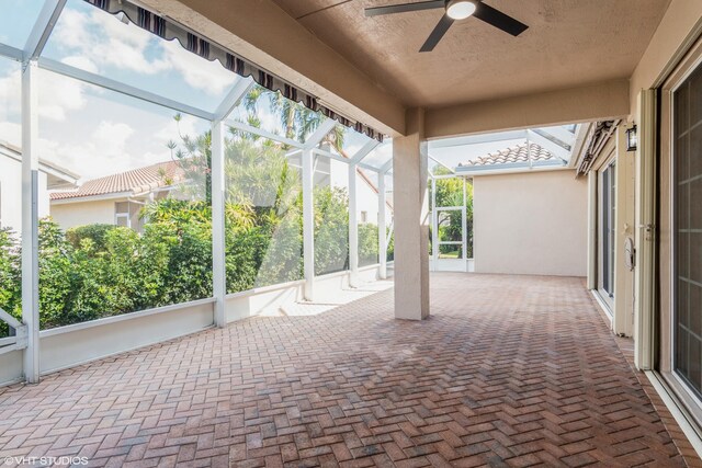 exterior space featuring glass enclosure and ceiling fan