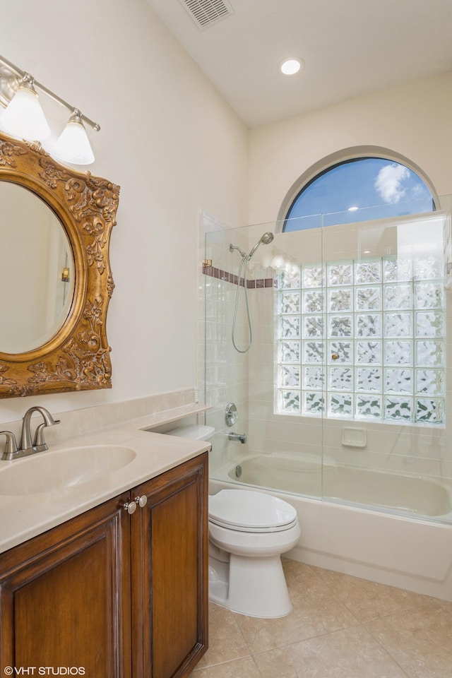 full bathroom featuring tile patterned flooring, vanity, tiled shower / bath combo, and toilet