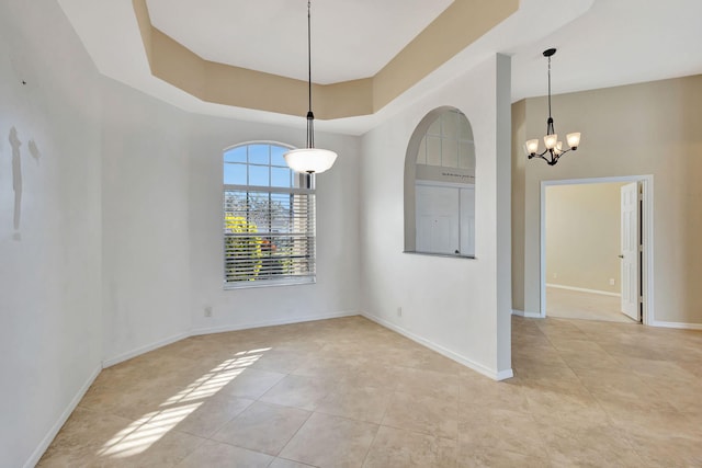 unfurnished room with light tile patterned floors, a towering ceiling, a raised ceiling, and a notable chandelier