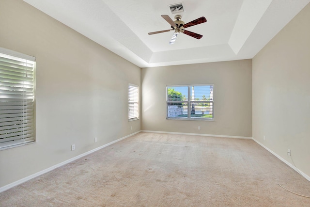 spare room featuring ceiling fan, a raised ceiling, and light carpet