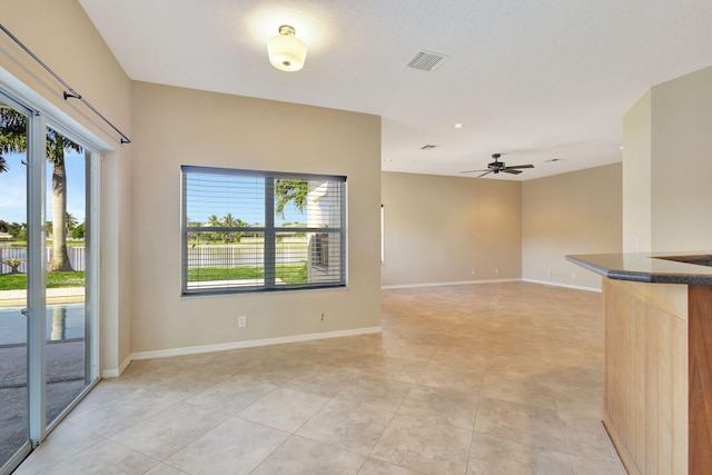 tiled empty room featuring ceiling fan