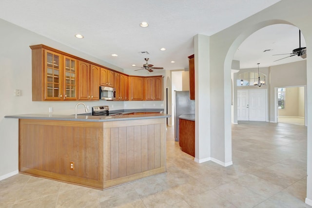 kitchen with kitchen peninsula, pendant lighting, stainless steel appliances, and ceiling fan with notable chandelier