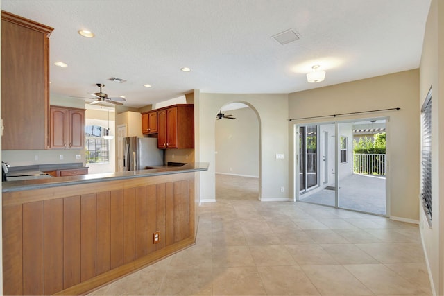 kitchen featuring a textured ceiling, stainless steel refrigerator, kitchen peninsula, and plenty of natural light