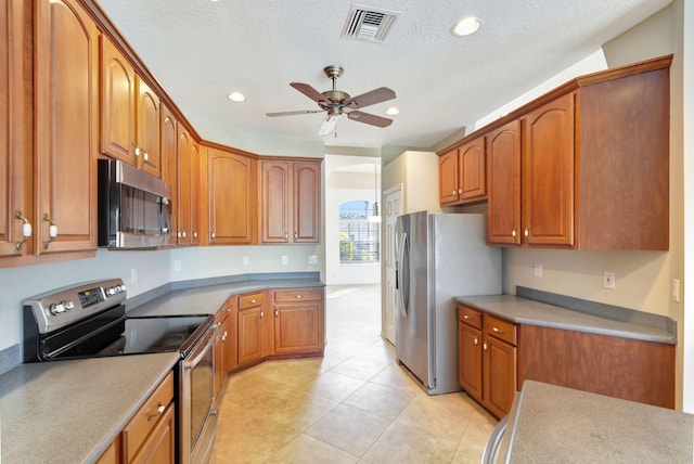 kitchen with appliances with stainless steel finishes, a textured ceiling, light tile patterned floors, and ceiling fan