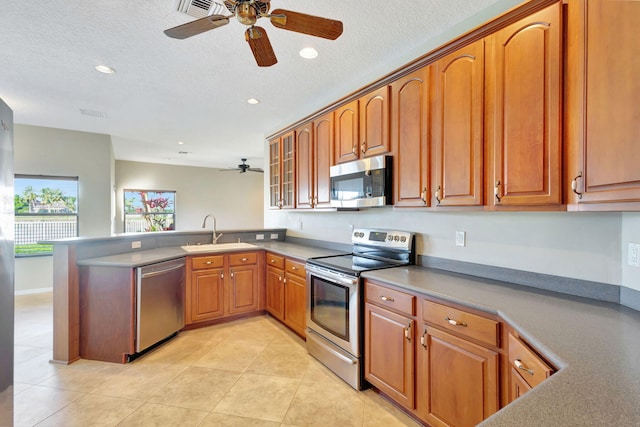 kitchen featuring sink, ceiling fan, light tile patterned floors, appliances with stainless steel finishes, and kitchen peninsula