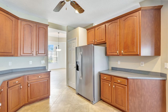 kitchen featuring stainless steel refrigerator with ice dispenser, a textured ceiling, ceiling fan, decorative light fixtures, and light tile patterned flooring