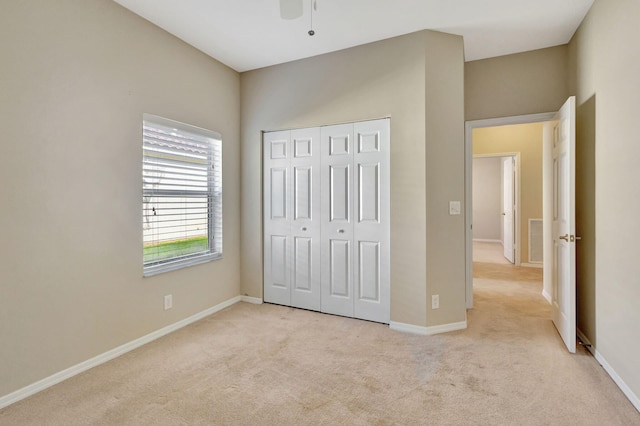 unfurnished bedroom with ceiling fan, light colored carpet, and a closet