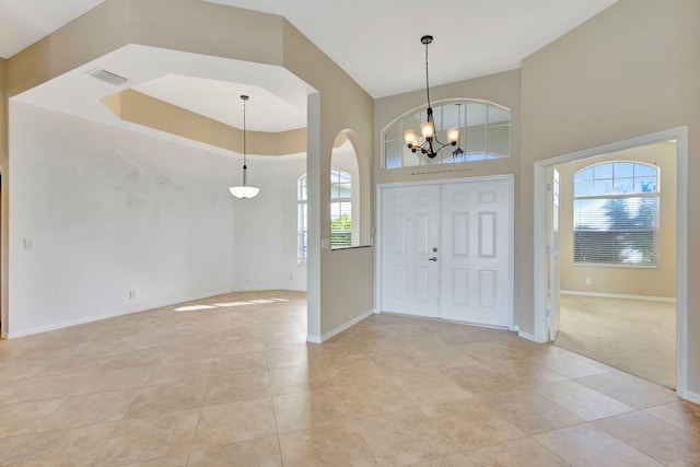 tiled entrance foyer with a towering ceiling and a chandelier