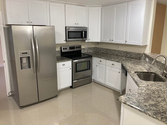 kitchen with sink, white cabinetry, stainless steel appliances, and dark stone counters