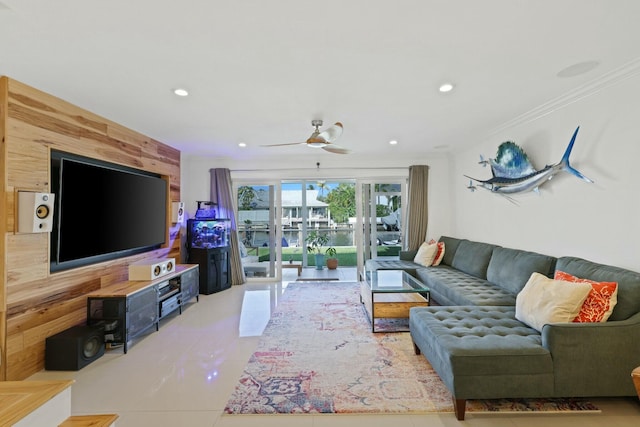 living room with ceiling fan, wood walls, light tile patterned floors, and ornamental molding