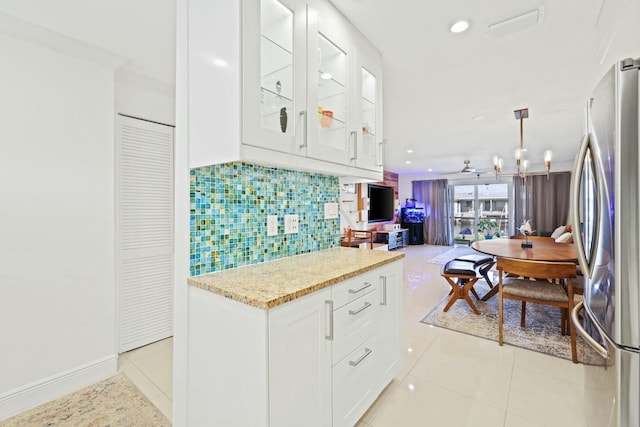 kitchen featuring white cabinets, pendant lighting, light tile patterned floors, and stainless steel refrigerator