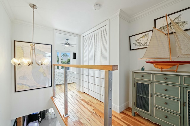 hall with light hardwood / wood-style floors, crown molding, and an inviting chandelier