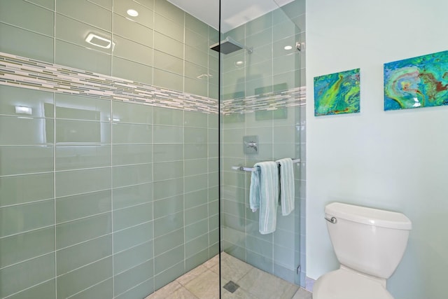 bathroom with toilet, tile patterned flooring, and tiled shower