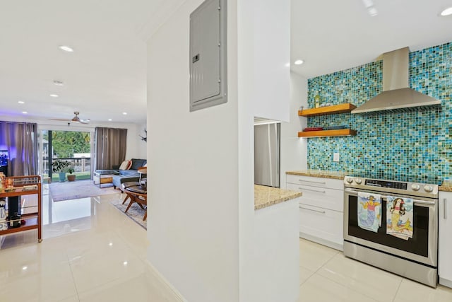 kitchen with tasteful backsplash, electric stove, wall chimney range hood, white cabinets, and electric panel