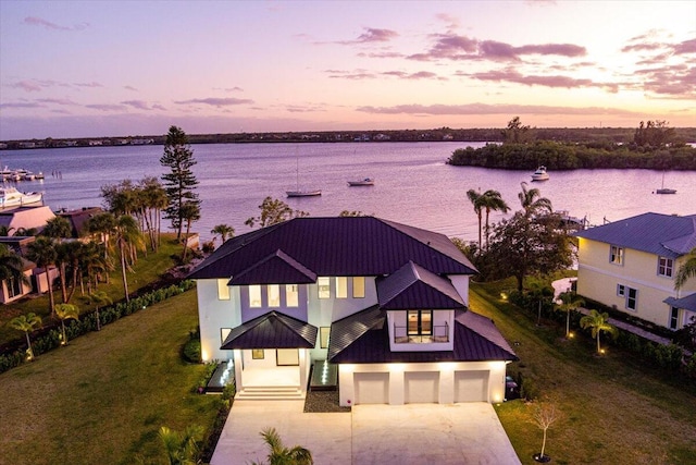 aerial view at dusk featuring a water view