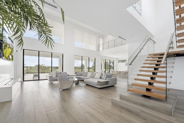 living room with light hardwood / wood-style floors and a towering ceiling