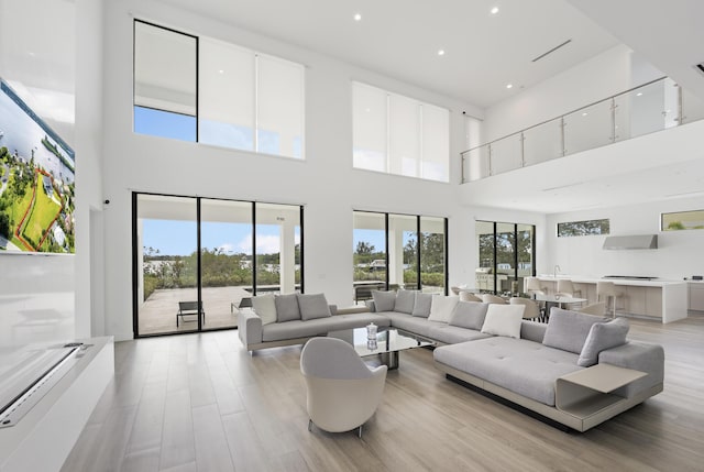 living room featuring light wood-type flooring and a towering ceiling