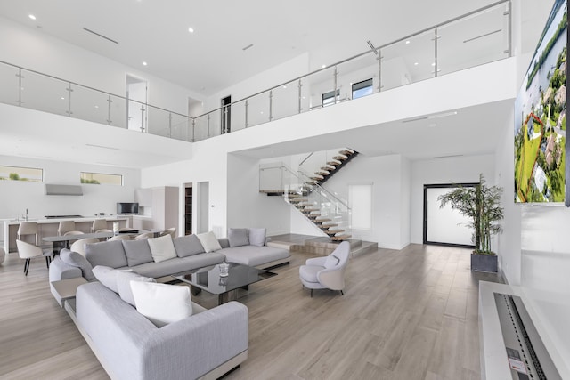 living room featuring sink, a high ceiling, and light hardwood / wood-style flooring