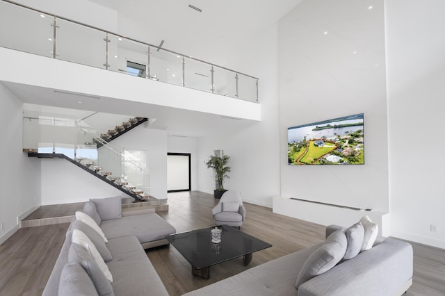 living room with light hardwood / wood-style flooring and a towering ceiling