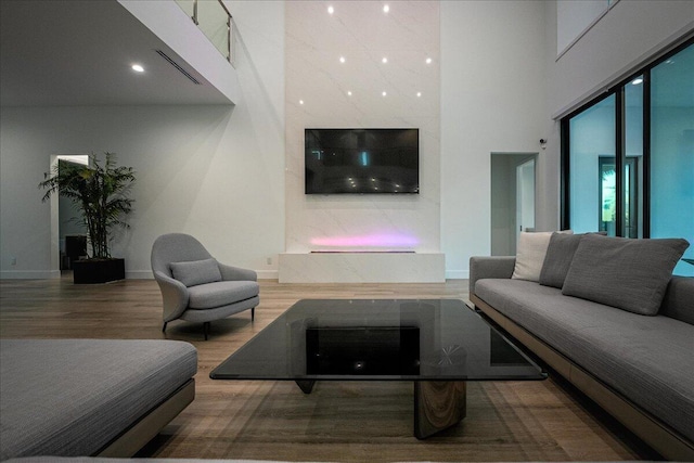 living room with wood-type flooring and a towering ceiling