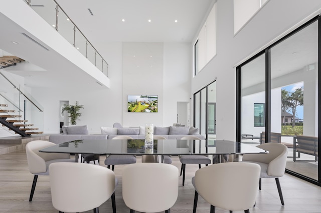 dining area with light hardwood / wood-style floors and a towering ceiling