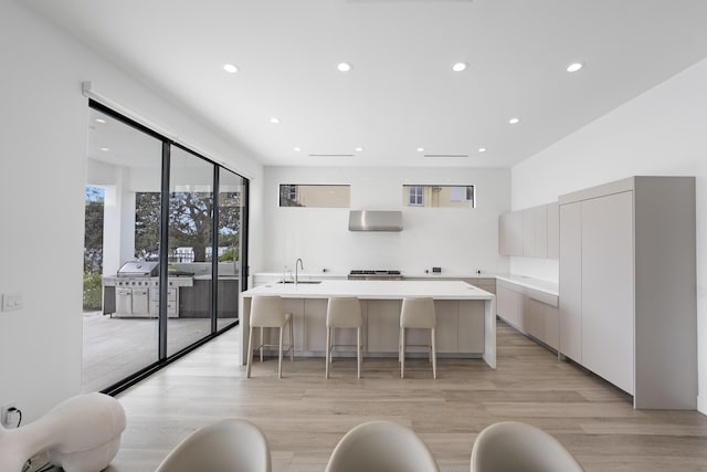 kitchen featuring a center island with sink, light hardwood / wood-style floors, and a kitchen bar