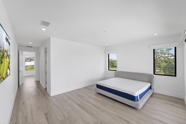 bedroom with multiple windows and light hardwood / wood-style flooring