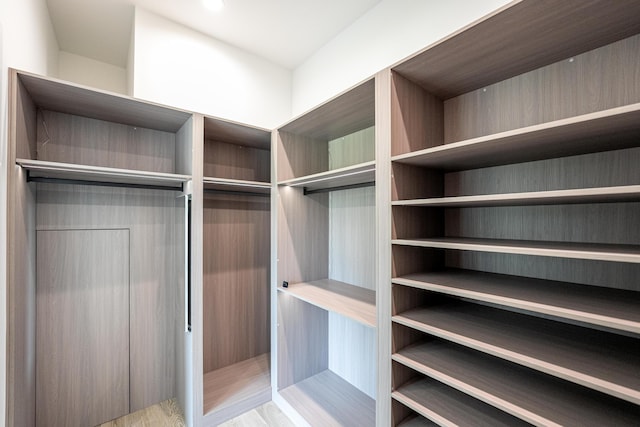 walk in closet with light hardwood / wood-style flooring