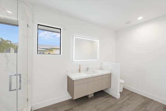 bathroom with wood-type flooring, vanity, toilet, and an enclosed shower