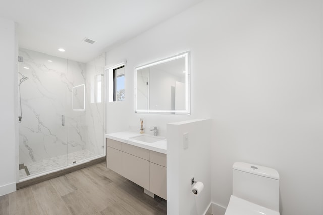 bathroom featuring hardwood / wood-style floors, vanity, toilet, and walk in shower