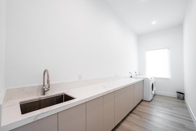 laundry area with cabinets, independent washer and dryer, light hardwood / wood-style flooring, and sink