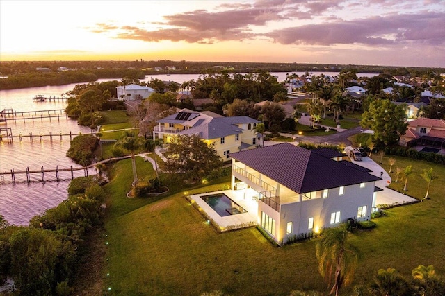 aerial view at dusk featuring a water view