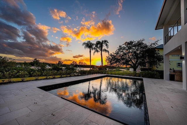 pool at dusk featuring a patio