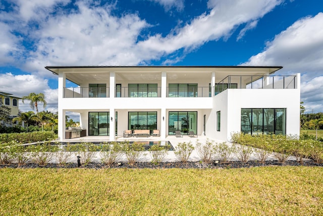 back of house with outdoor lounge area, a yard, a balcony, and a patio area