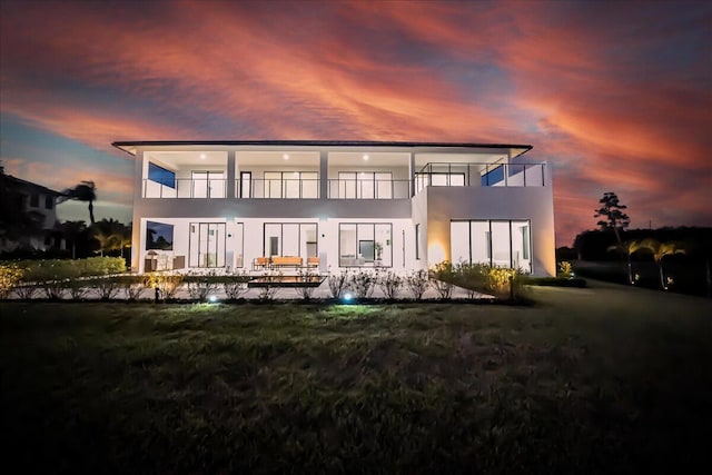 back house at dusk featuring a balcony